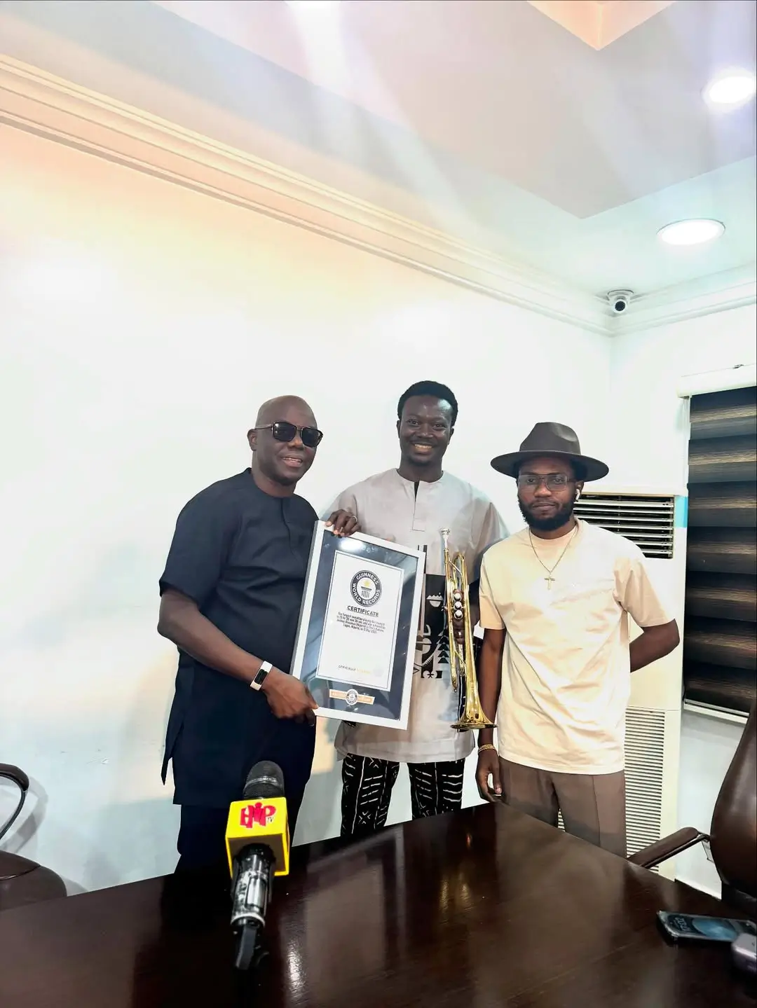 Joshua Olusanya presenting his Guinness World Record certificate to Ayo Animashaun at HipTV