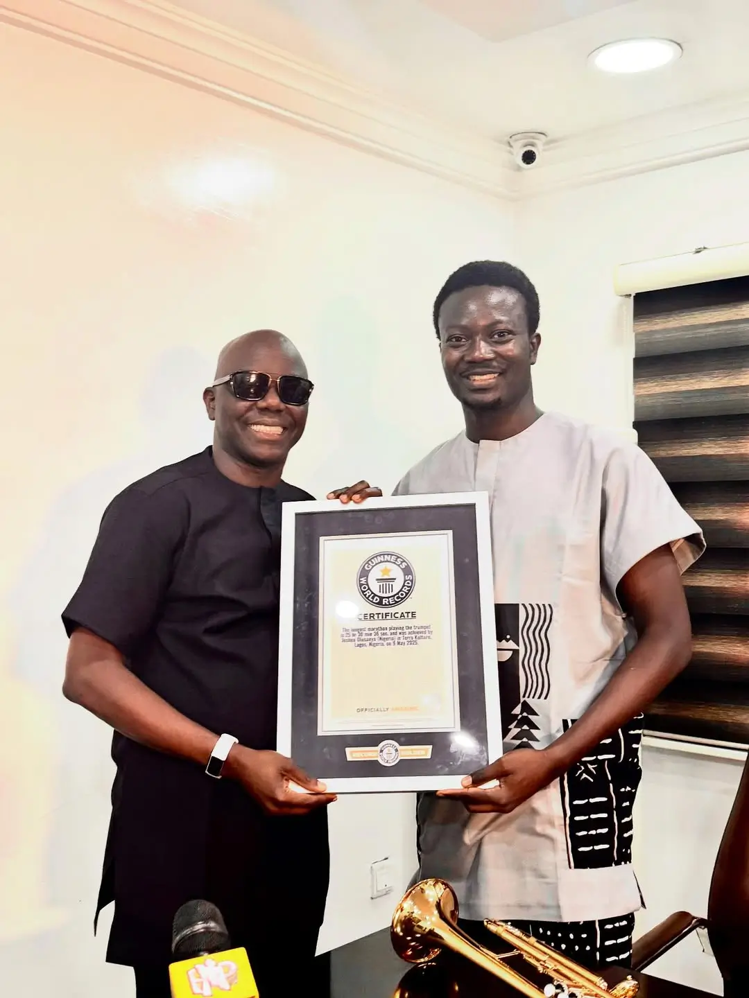 Joshua Olusanya presenting his Guinness World Record certificate to Ayo Animashaun at HipTV