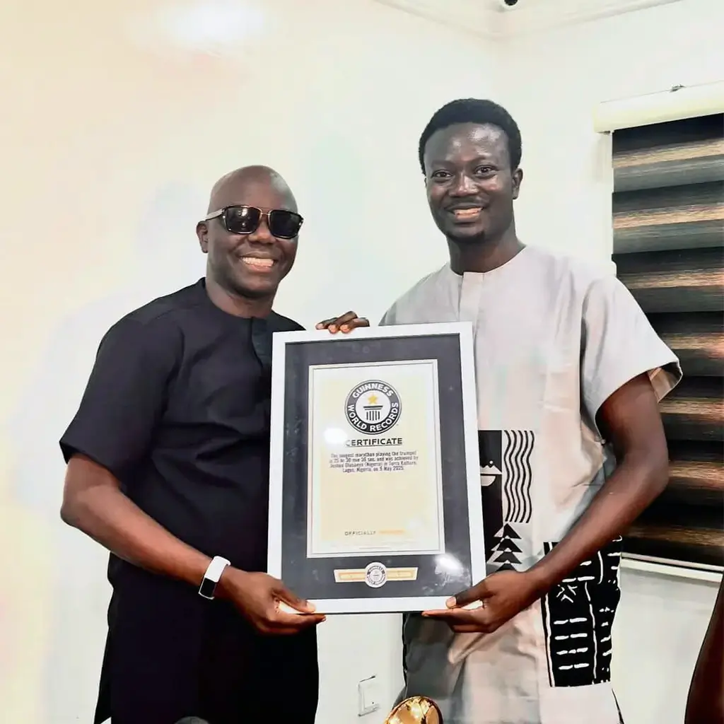 Joshua Olusanya presenting his Guinness World Record certificate to Ayo Animashaun at HipTV
